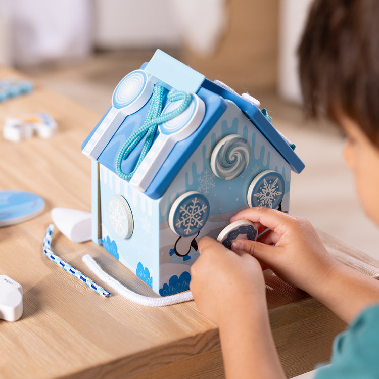 A kid playing with The Melissa & Doug Winter Frost Wooden Gingerbread House Play Set for Boys and Girls 3+ 
