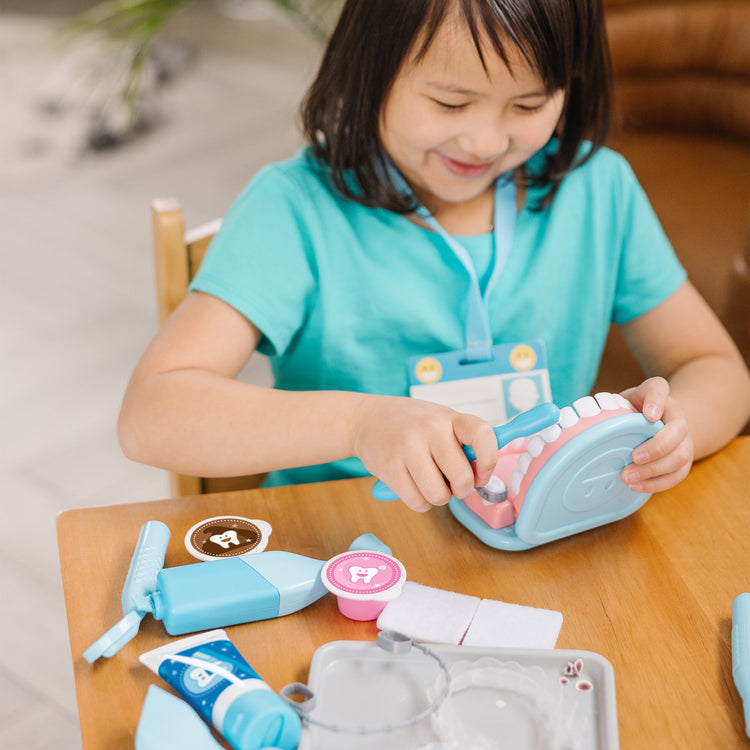 A kid playing with The Melissa & Doug Super Smile Dentist Kit With Pretend Play Set of Teeth And Dental Accessories (25 Toy Pieces)