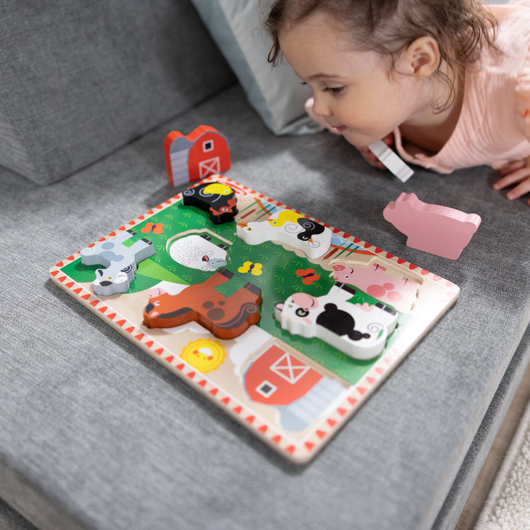A kid playing with The Melissa & Doug Farm Wooden Chunky Puzzle (8 pcs)