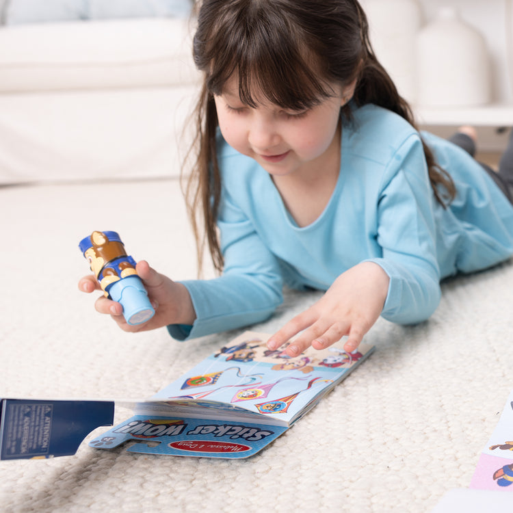 A kid playing with The Melissa & Doug Sticker WOW!™ PAW Patrol Chase Bundle: 24-Page Activity Pad, Sticker Stamper, 500 Stickers, Mini Pad, Arts and Crafts Fidget Toy Collectible Character