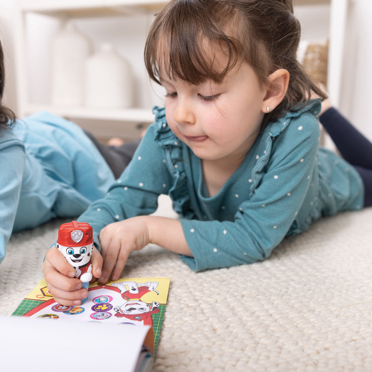 A kid playing with The Melissa & Doug Sticker WOW!™ PAW Patrol Marshall Bundle: 24-Page Activity Pad, Sticker Stamper, 500 Stickers, Mini Pad, Arts and Crafts Fidget Toy Collectible Character