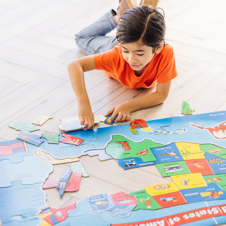 A kid playing with The Melissa & Doug USA Map Floor Puzzle - 51 Pieces (2 x 3 feet)