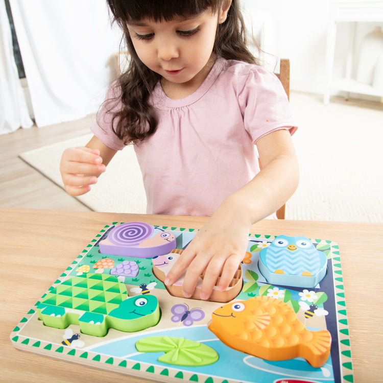 A kid playing with The Forest Friends Touch & Feel Puzzle