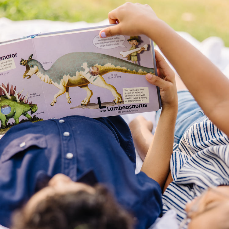 A kid playing with The Melissa & Doug Children's Book - Poke-A-Dot: Dinosaurs A to Z (Board Book with Buttons to Pop)