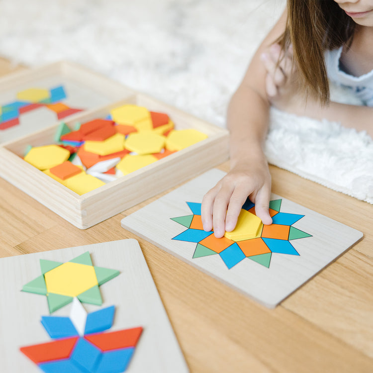 A kid playing with The Melissa & Doug Pattern Blocks and Boards - Classic Toy With 120 Solid Wood Shapes and 5 Double-Sided Panels, Multi-Colored Animals Puzzle