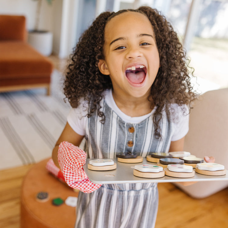 A kid playing with The Melissa & Doug Slice and Bake Wooden Cookie Play Food Set
