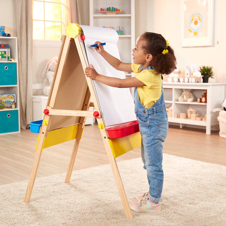 A kid playing with The Melissa & Doug Art Essentials Easel Pad (17 x 20 inches) With 50 Sheets of White Bond Paper
