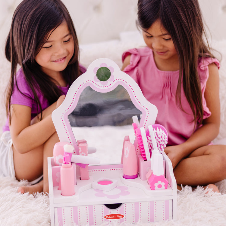 A kid playing with The Melissa & Doug Wooden Beauty Salon Play Set With Vanity and Accessories (18 pcs)