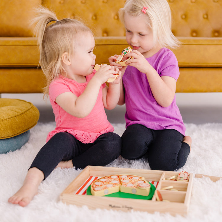 A kid playing with The Melissa & Doug Wooden Pizza Party Play Food Set With 36 Toppings