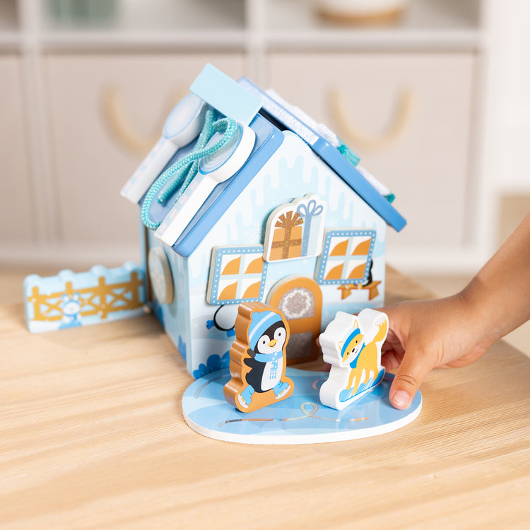A kid playing with The Melissa & Doug Winter Frost Wooden Gingerbread House Play Set for Boys and Girls 3+ 