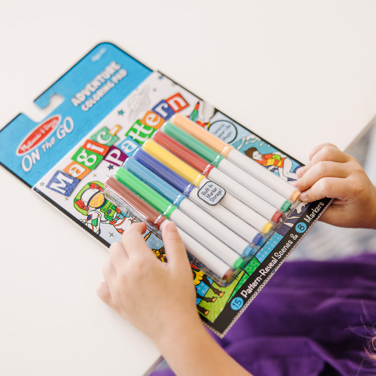 A kid playing with The Melissa & Doug Magic-Pattern Kids’ Adventure Marker Coloring Pad On the Go Travel Activity