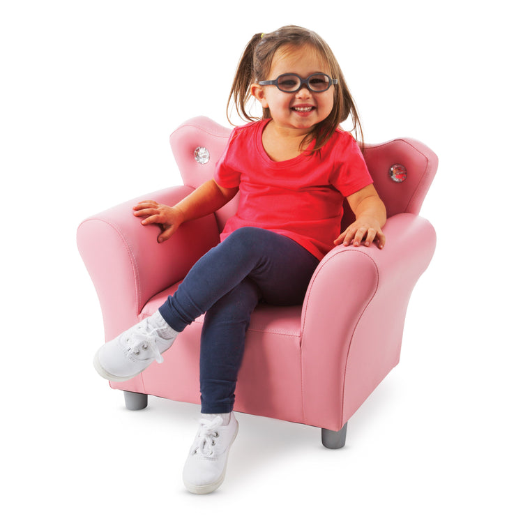 A child on white background with The Melissa & Doug Pink Faux Leather Child’s Crown-Back Armchair (Kid’s Furniture)