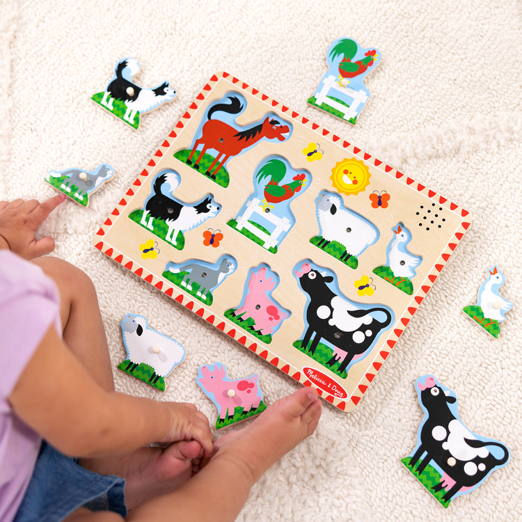 A kid playing with The Melissa & Doug Wooden Sound Puzzle 2-Pack for Toddler and Preschool Boys and Girls – Farm Animals, Vehicles