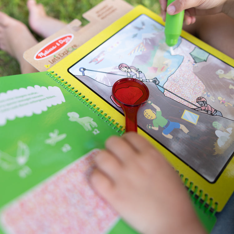 A kid playing with The Melissa & Doug Let’s Explore Water Wow! Outdoor Adventure Deluxe Water-Reveal Pad – Reusable On The Go Travel Activity