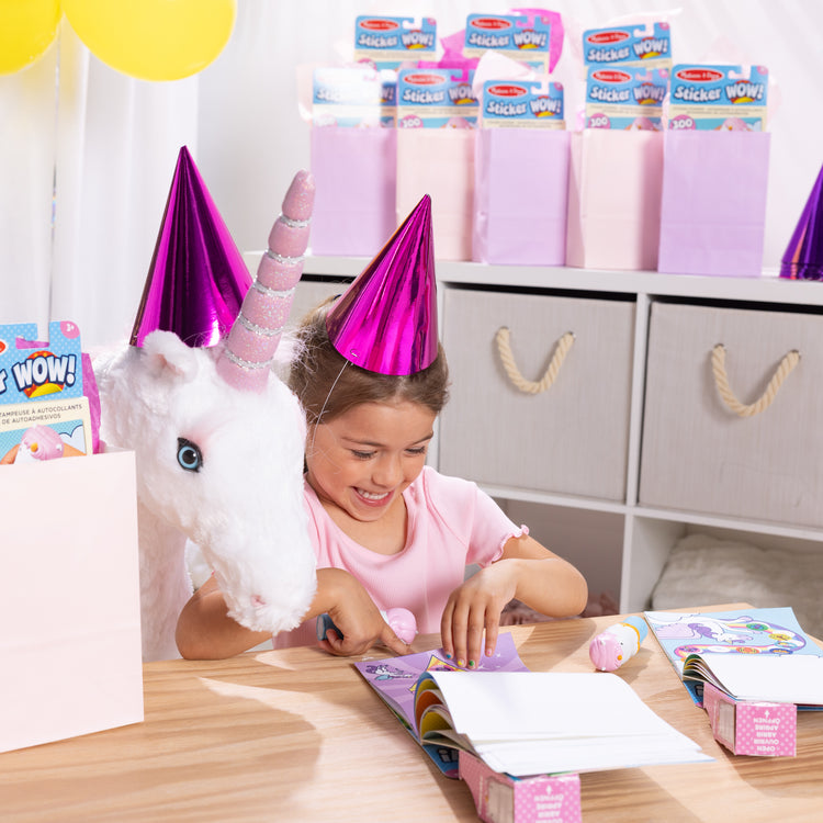 A kid playing with The Melissa & Doug Sticker WOW!™ 24-Page Activity Pad and Sticker Stamper, 300 Stickers, Arts and Crafts Fidget Toy Collectible Character – Unicorn