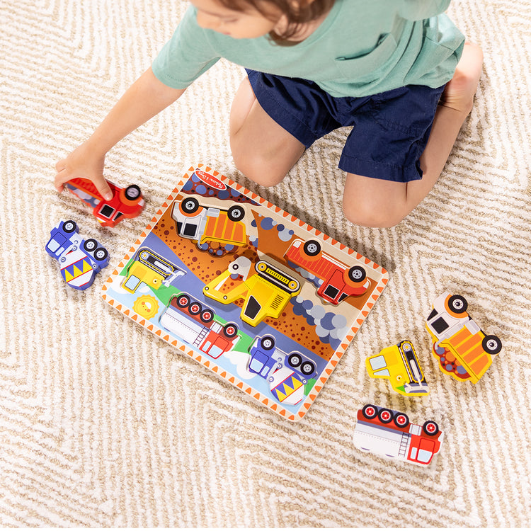 A kid playing with The Melissa & Doug Construction Vehicles Wooden Chunky Puzzle (6 pcs)