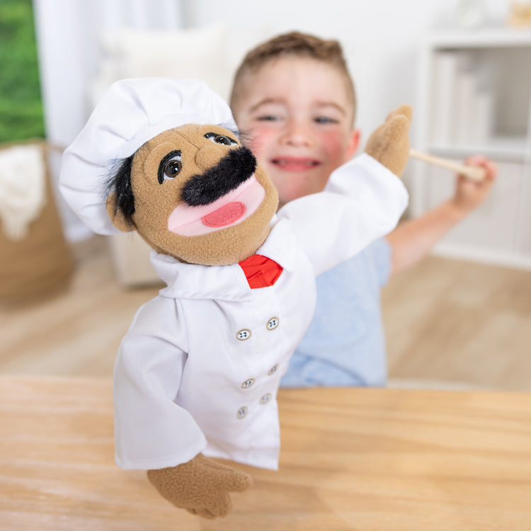 A kid playing with The Melissa & Doug Chef Puppet (Al Dente) with Detachable Wooden Rod