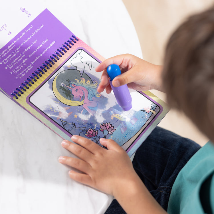 A kid playing with The Melissa & Doug Water WOW! Reusable Water-Reveal Coloring Activity Pad Travel Toy – Unicorn