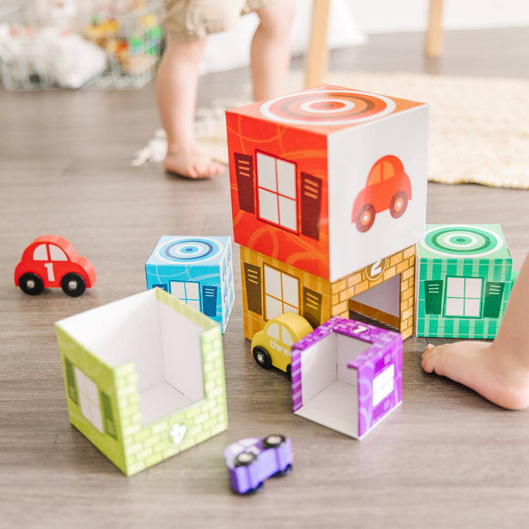 A kid playing with The Melissa & Doug Nesting and Sorting Garages and Cars With 7 Graduated Garages and 7 Stackable Wooden Cars