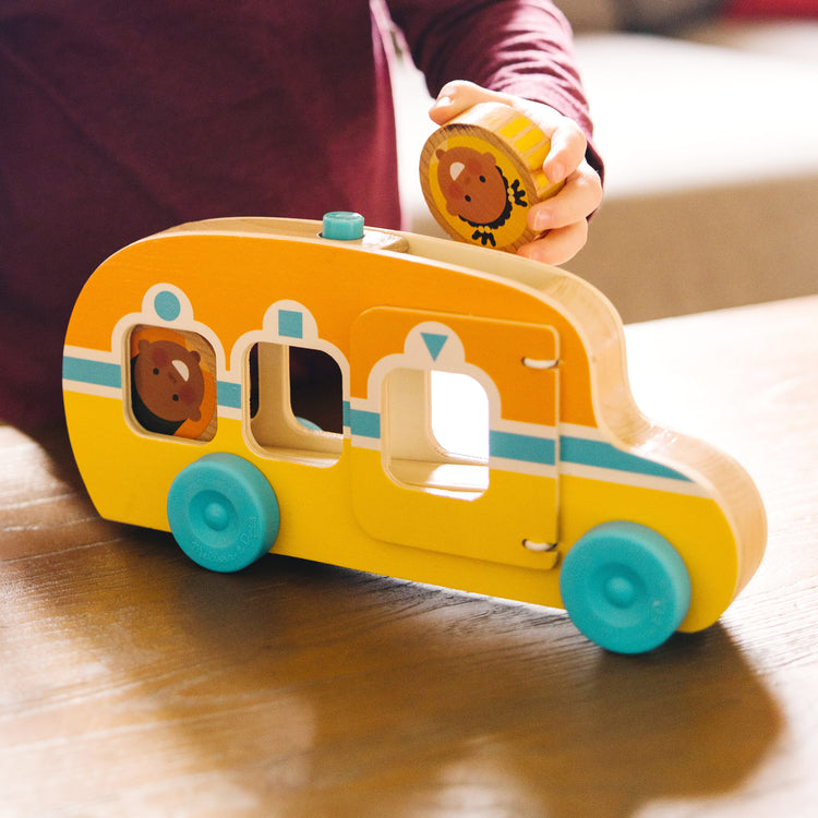 A kid playing with The Melissa & Doug GO Tots Wooden Roll & Ride Bus with 3 Disks