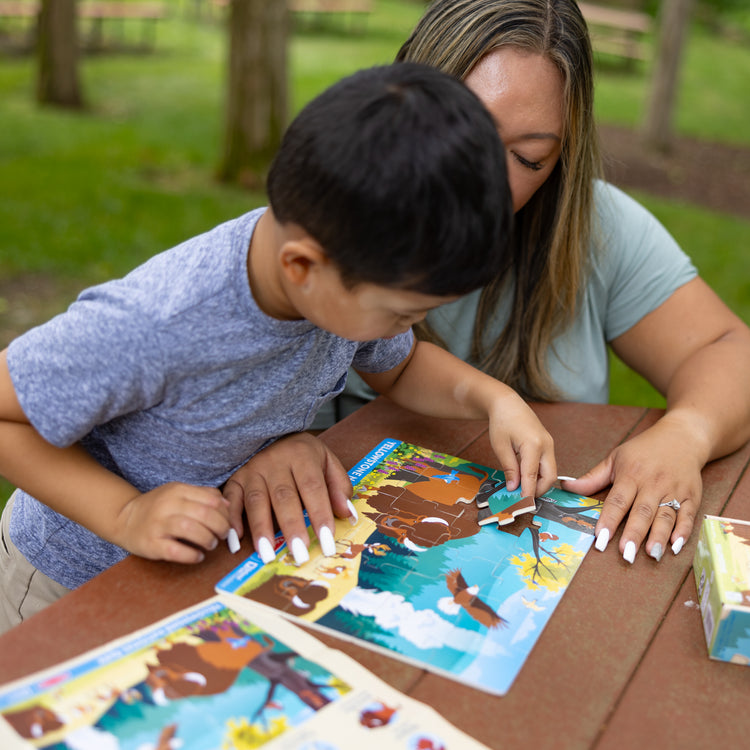 A kid playing with The Melissa & Doug Yellowstone National Park Wooden Jigsaw Puzzle – 24 Pieces, Animal and Plant ID Guide