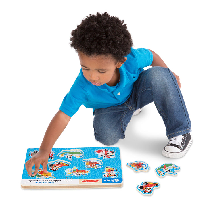 A child on white background with The Melissa & Doug Disney Mickey Mouse and Friends Vehicles Sound Puzzle (8 pcs)