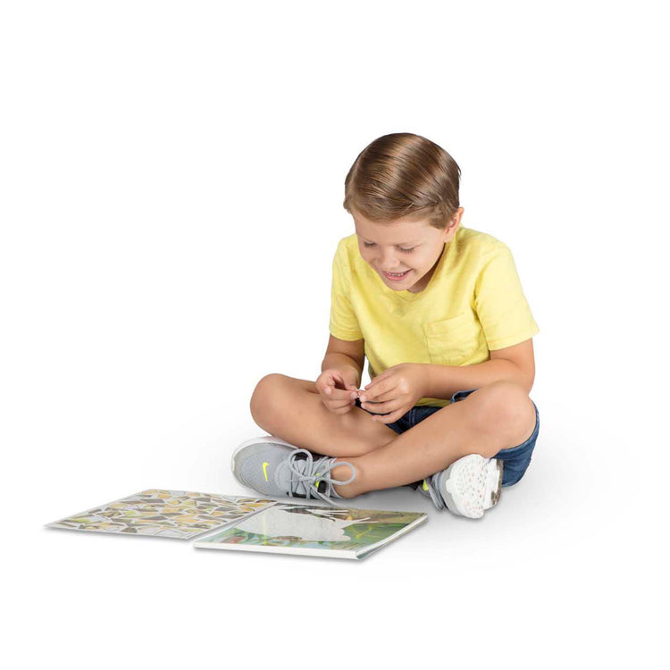 A child on white background with The Melissa & Doug Mosaic Sticker Pad Nature (12 Color Scenes to Complete with 850+ Stickers)