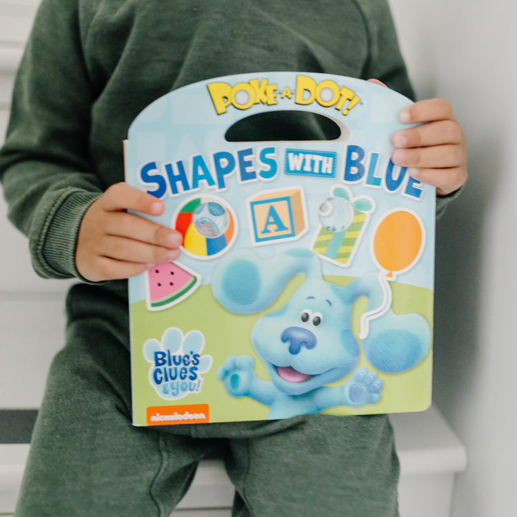 A kid playing with The Melissa & Doug Blue's Clues & You! Children's Book - Poke-A-Dot: Shapes with Blue
