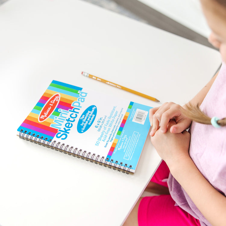 A kid playing with The Melissa & Doug Mini Sketch Pad of Paper (6 x 9 inches) - 50 Sheets, 3-Pack