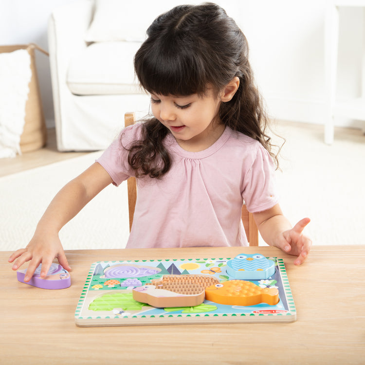 A kid playing with The Forest Friends Touch & Feel Puzzle