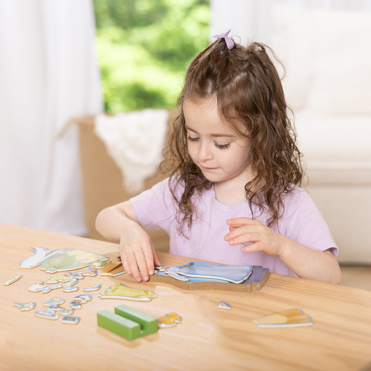 A kid playing with The Melissa & Doug Disney Princess Tiana Magnetic Dress-Up Wooden Doll Pretend Play Set (30+ pcs)

