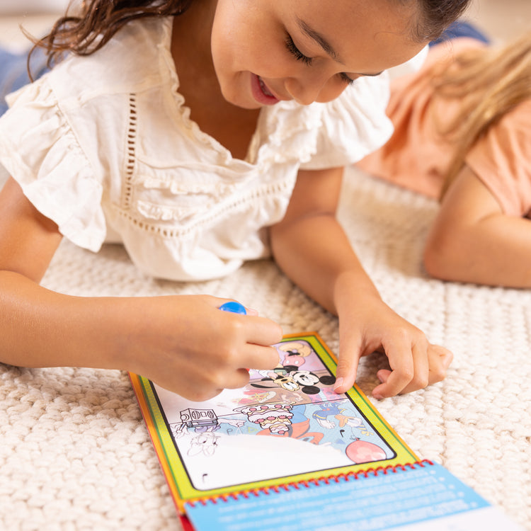 A kid playing with The Melissa & Doug Water WOW! Disney Mickey & Friends Activity Pad - Reusable Reveal Pages - Ages 3+