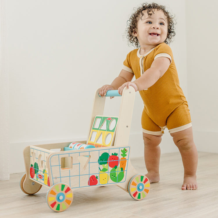 child playing with wooden grocery cart toy