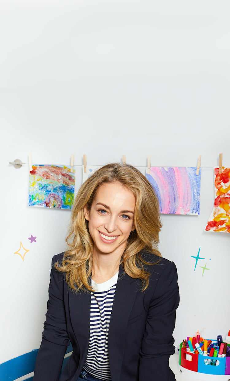 Headshot of Dr. Becky sitting in a room with children's finger painting art behind her