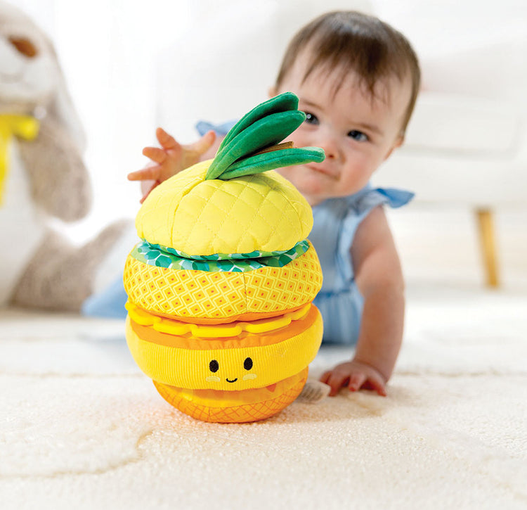 toddler reaching for soft pineapple stacker toy