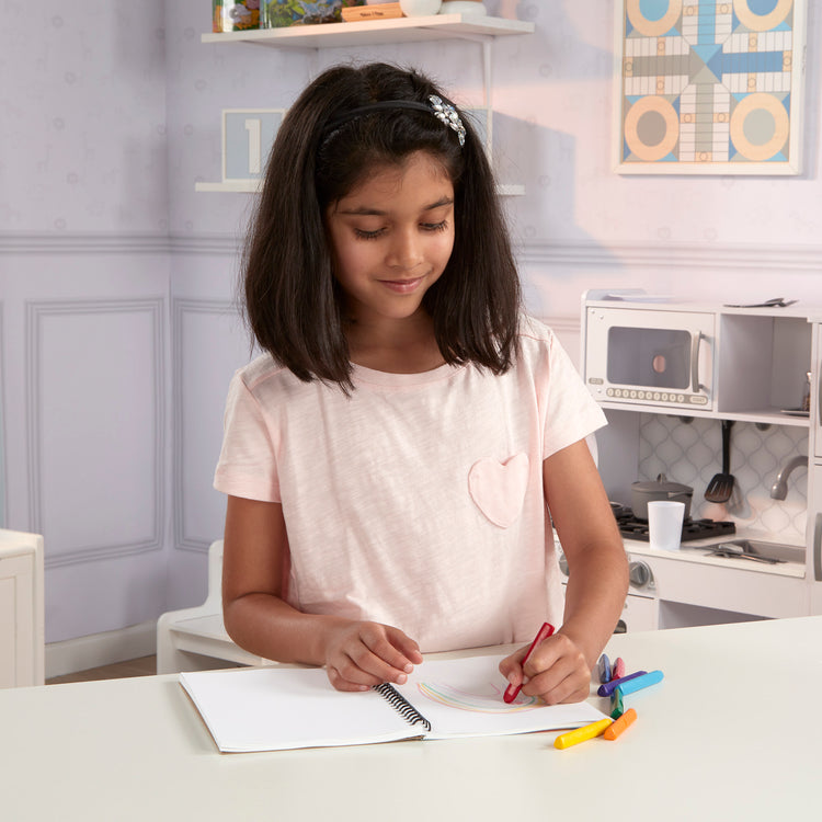 A kid playing with The Melissa & Doug Mini Sketch Pad of Paper (6 x 9 inches) - 50 Sheets, 3-Pack