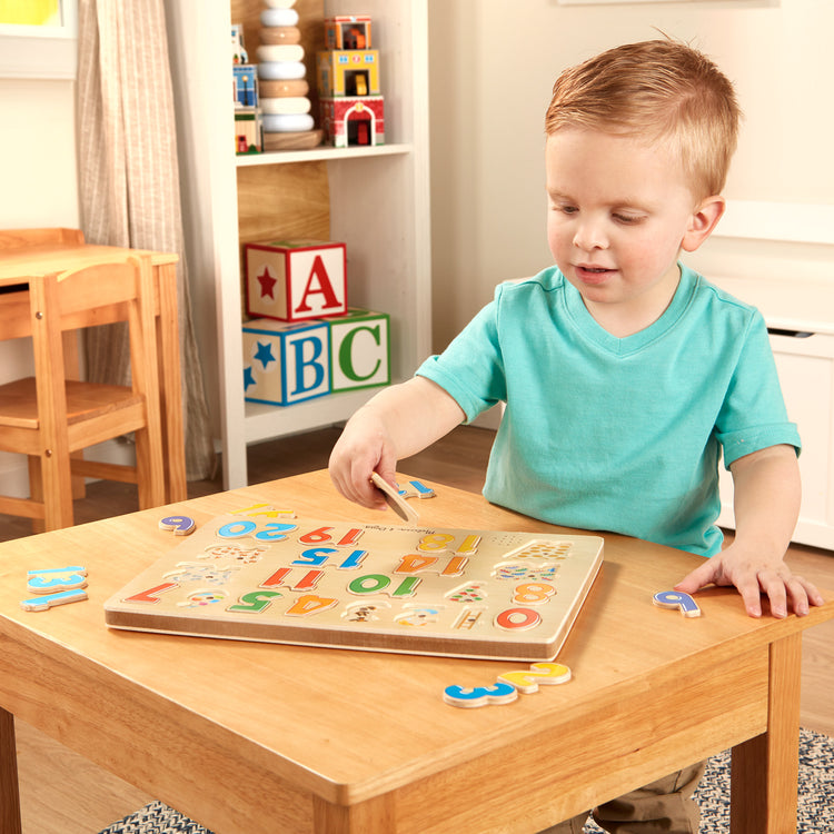 A kid playing with The Melissa & Doug Numbers Sound Puzzle - Wooden Puzzle With Sound Effects (21 pcs)