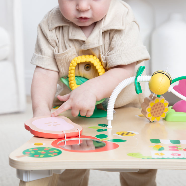 A kid playing with The Farmers Market 3 in 1 Activity Center