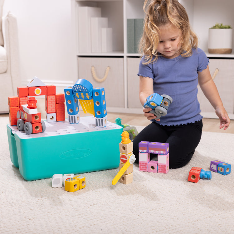 A kid playing with The Melissa & Doug Blockables™ Deluxe City Snap And Play Amazon Exclusive, Mix and Match Connectable Wooden Building Blocks Play Set With Storage Bin and Play Lid (122 Pcs)