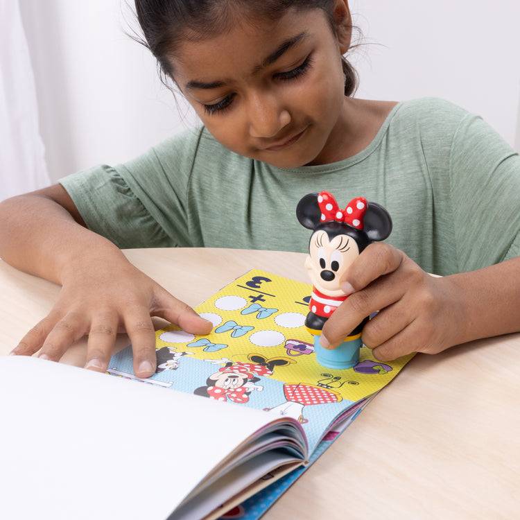 A kid playing with The Melissa & Doug Sticker WOW!™ Disney Minnie Mouse Bundle: 24-Page Activity Pad, Sticker Stamper, 500 Stickers, Mini Pad, Arts and Crafts Fidget Toy Collectible Character