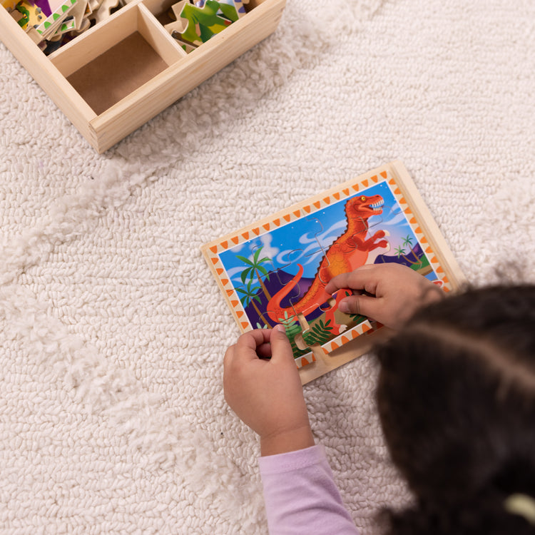 A kid playing with The Melissa & Doug Dinosaurs 4-in-1 Wooden Jigsaw Puzzles in a Storage Box (48 pcs)