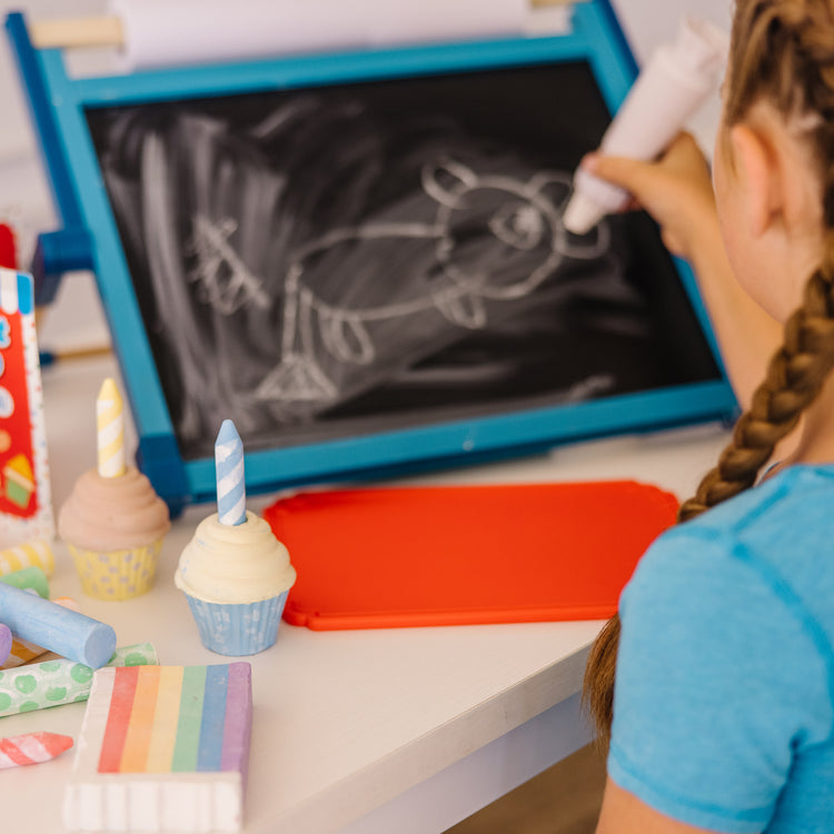 A kid playing with The Melissa & Doug Sweet Shop Multi-Colored Chalk and Holders Play Set - 33 Pieces, Great Gift for Girls and Boys