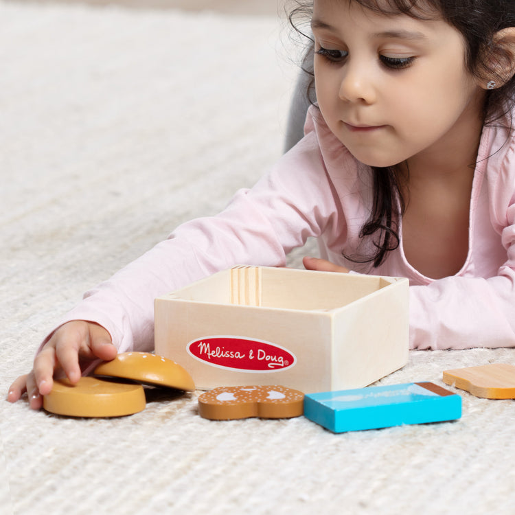 A kid playing with The Melissa & Doug Wooden Food Groups Play Food Set – Grains