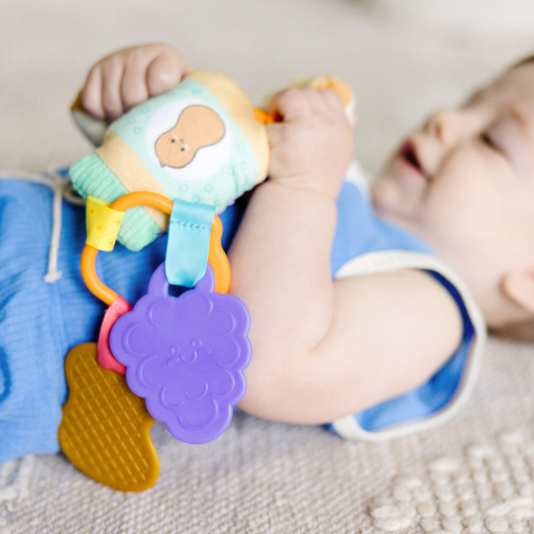 A kid playing with The Melissa & Doug Multi-Sensory PB&J Take-Along Clip-On Infant Toy