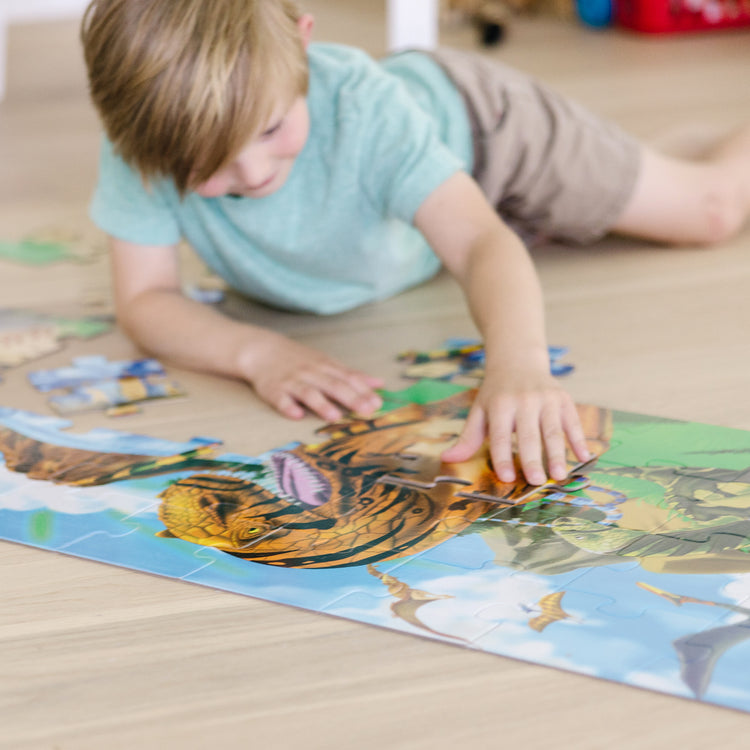 A kid playing with The Melissa & Doug Land of Dinosaurs Floor Puzzle (48 pcs, 4 feet long)