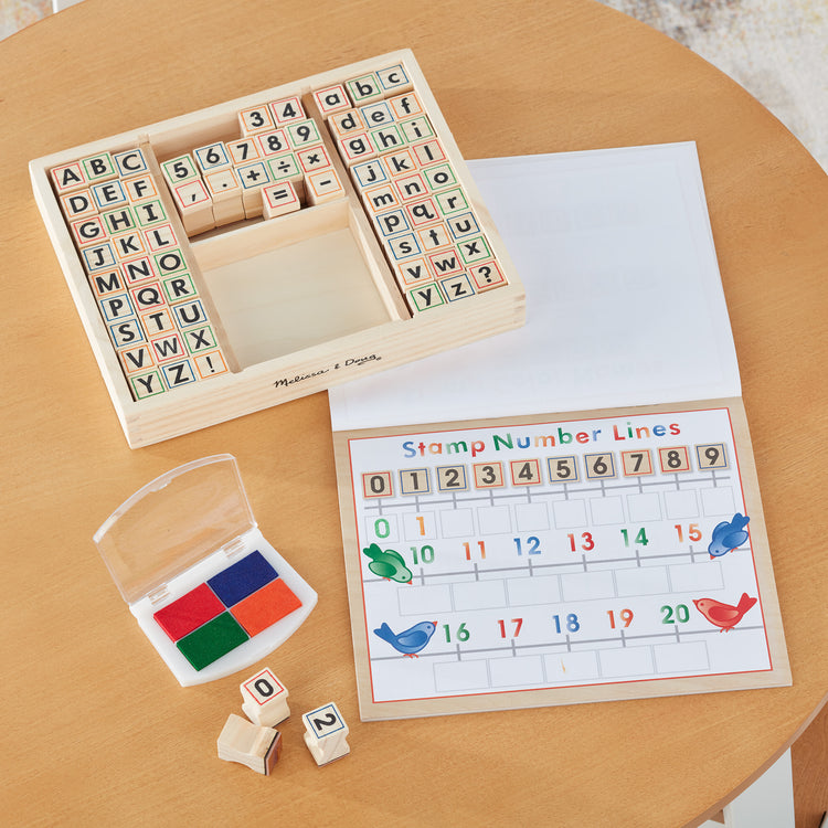 A playroom scene with The Melissa & Doug Deluxe Letters and Numbers Wooden Stamp Set ABCs 123s With Activity Book, 4-Color Stamp Pad