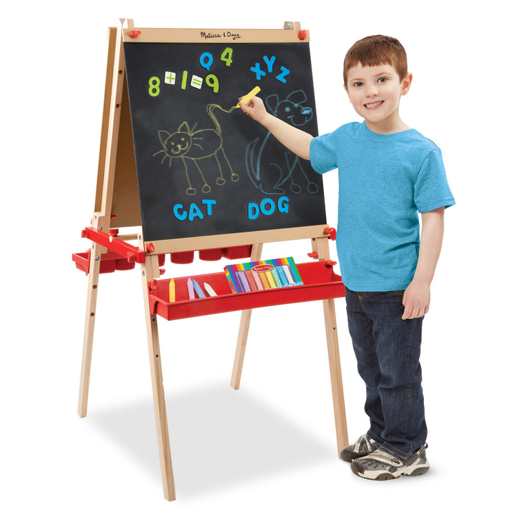 A child on white background with The Melissa & Doug Deluxe Magnetic Standing Art Easel With Chalkboard, Dry-Erase Board, and 39 Letter and Number Magnets