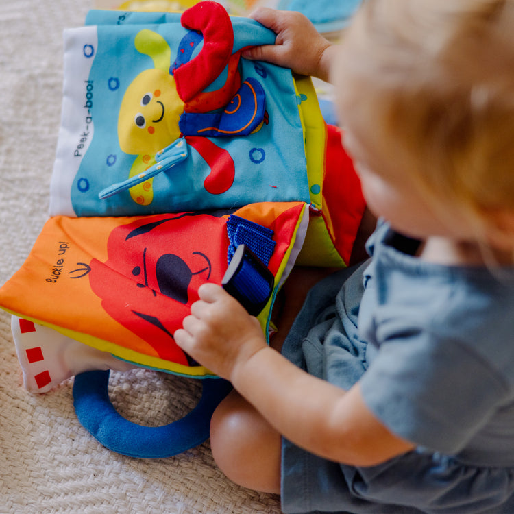 A kid playing with The Melissa & Doug K’s Kids My First Activity Book 8-Page Soft Book for Babies and Toddlers