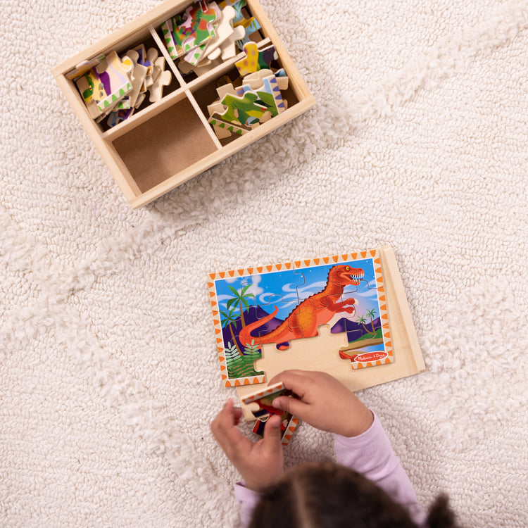 A kid playing with The Melissa & Doug Dinosaurs 4-in-1 Wooden Jigsaw Puzzles in a Storage Box (48 pcs)