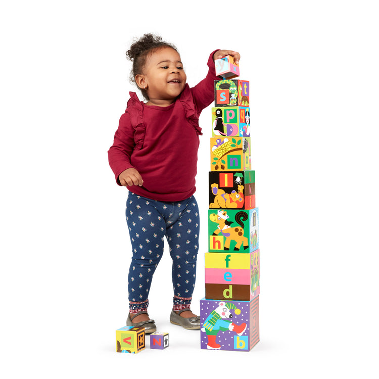 A child on white background with The Melissa & Doug Deluxe 10-Piece Alphabet Nesting and Stacking Blocks
